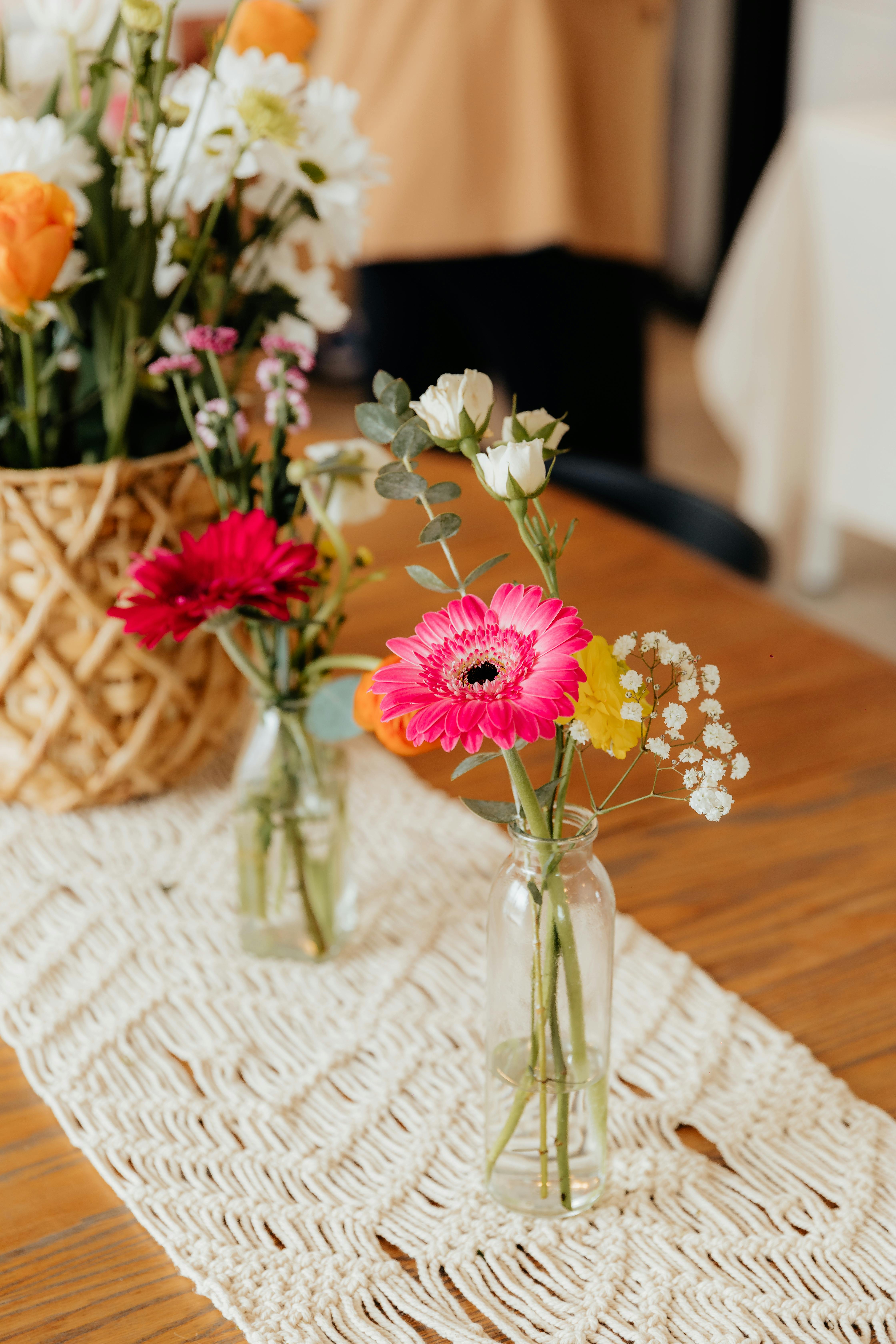 Glass bud vases with colourful flowers on macrame runner