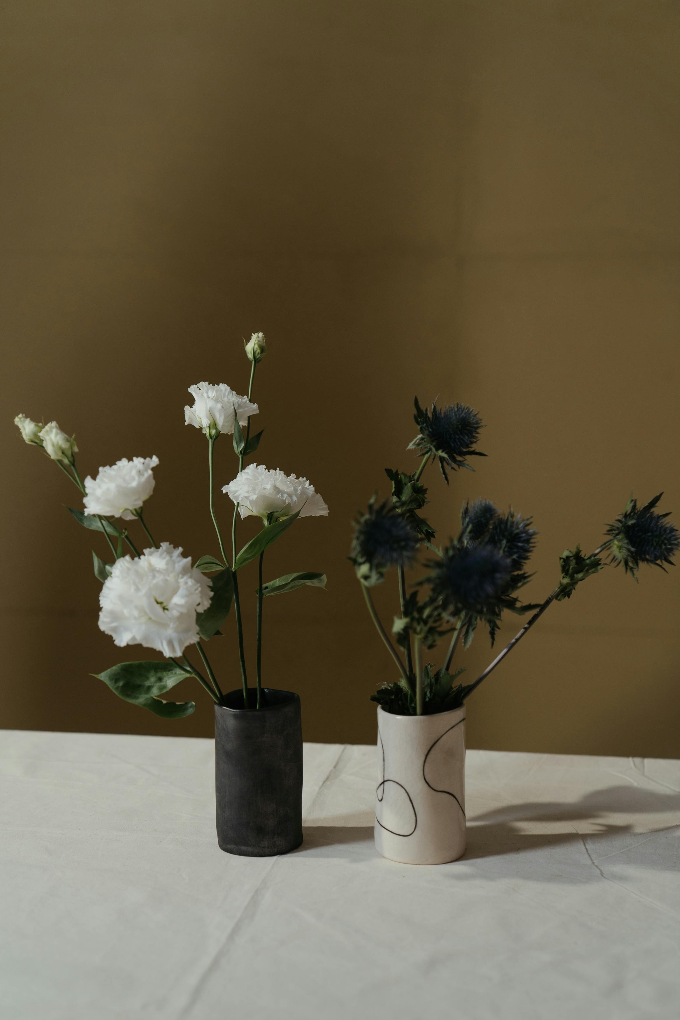 White lisianthus and blue thistle in ceramic vases